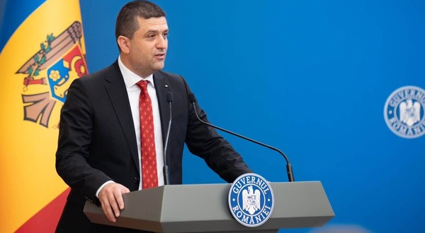Ministrul interimar al Apărării, Radu Miruță, în timpul unei conferințe de presă la Guvernul României. Poartă un costum negru, o cămașă labă și o cravată roșie