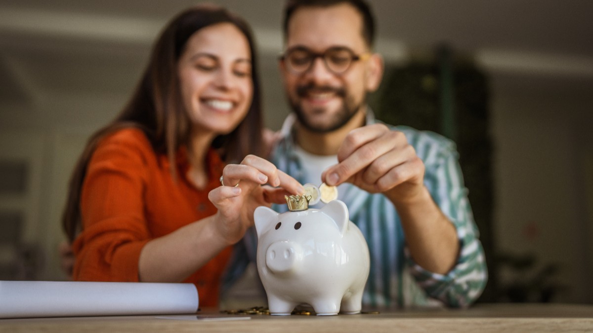 Doi soți în timp ce fac economii și pun banii într-o pușculiță
