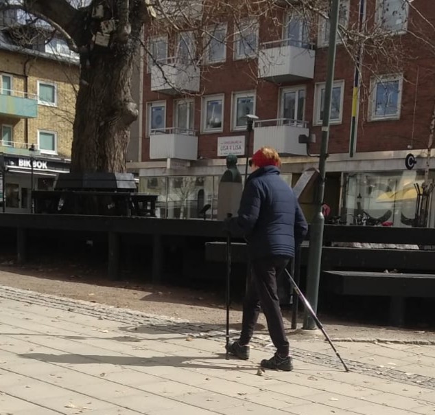 O localnică în vârstă din comuna Pitea, în centrul localității, la plimbare cu bețele de mers nordic