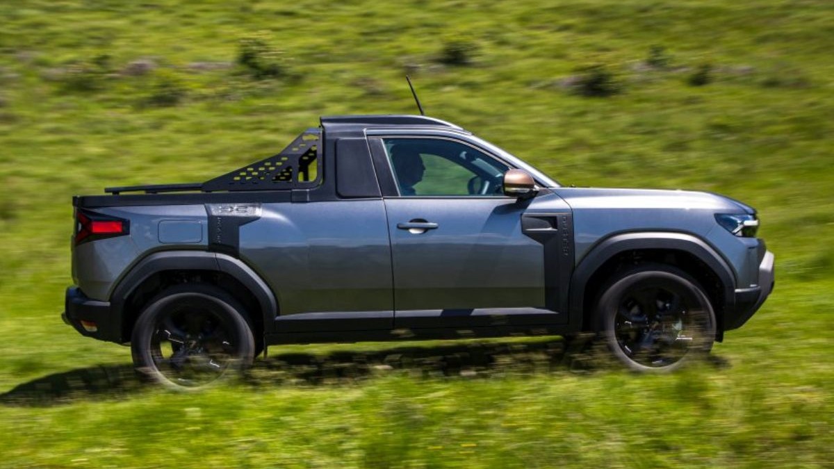 Masina Dacia Duster varianta Pick Up poza din profil pe un camp verde