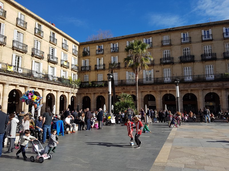 Bilbao, Spania - ianuarie 2017: clădirea Euskaltzaindia din Plaza Nueva plină de oameni și copii care poartă tricoul Athletic of Bilbao jucând fotbal. Foto: Shutterstock
