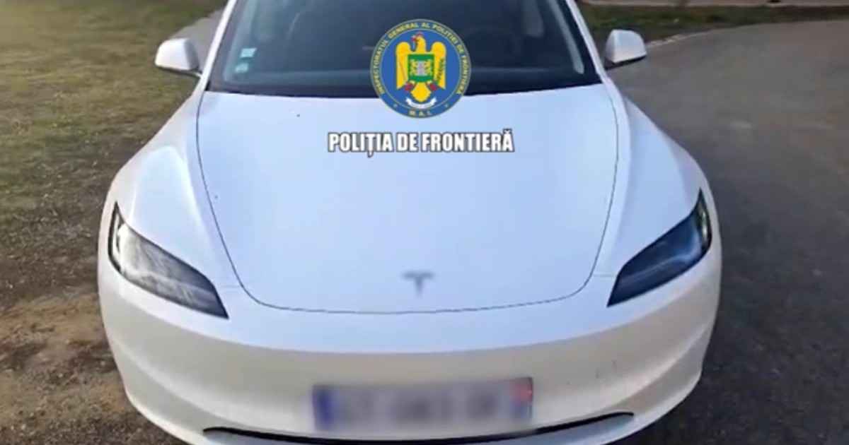 O mașină albă marca Tesla, fotografiată din față. Aceasta are numărul de înmatriculare blurat. Pe imagine se observă un watermark: „Poliția de Frontieră”