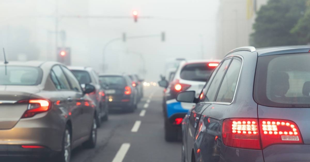masini in trafic asteptand la semafor intr-o vreme cețoasă