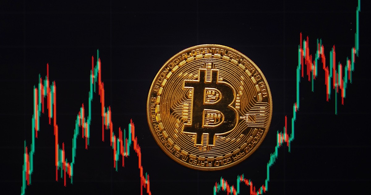 O monedă Bitcoin se află pe un ecran care arată cursul de schimb Bitcoin - dolar american.