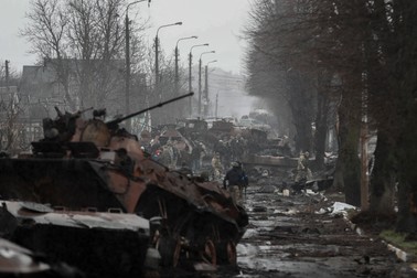 Soldații ucraineni, ajunși în Bucha după retragerea rușilor, se uită la tancurile distruse de ei, după ce au pus la cale o ambuscadă, pe 3 aprilie 2022. Foto: EPA