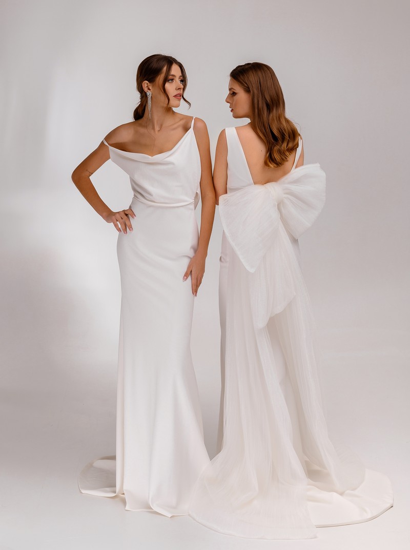 Two fashion women brunette models in bridal dresses and wedding hairstyles standing together posing on white background. Adorable brides. Wedding jewelry, haircut concept. Wedding salon.