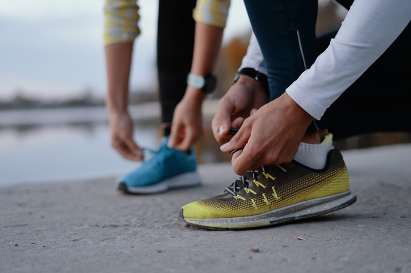 Tying sports shoes. Young couple getting ready for running and fitness training outdoors. Sport, exercise, fitness, workout. Healthy lifestyle.