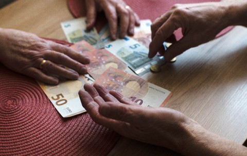 Doi bătrâni care numără bancnote euro