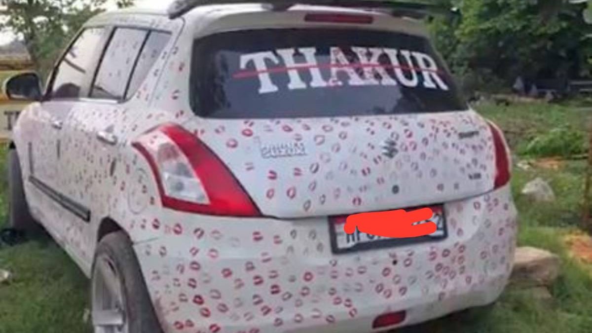 O mașină albă, văzută din spate, este acoperită aproape în întregime cu sute de urme de buze făcute cu ruj roșu și roz. Pe lunetă apare cuvântul „THAKUR”, scris cu litere mari, iar numărul de înmatriculare este acoperit în imagine.
