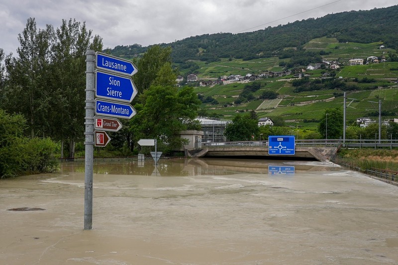 A picture taken on June 30, 2024 shows road signs above a flooded road near Sierre, western Switzerland. Ferocious storms and torrential rains that lashed France, Switzerland and Italy this weekend have left five people dead, local authorities said.,Image: 885957905, License: Rights-managed, Restrictions: , Model Release: no