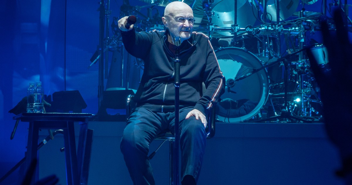 Phil Collins cântă așezat pe un scaun