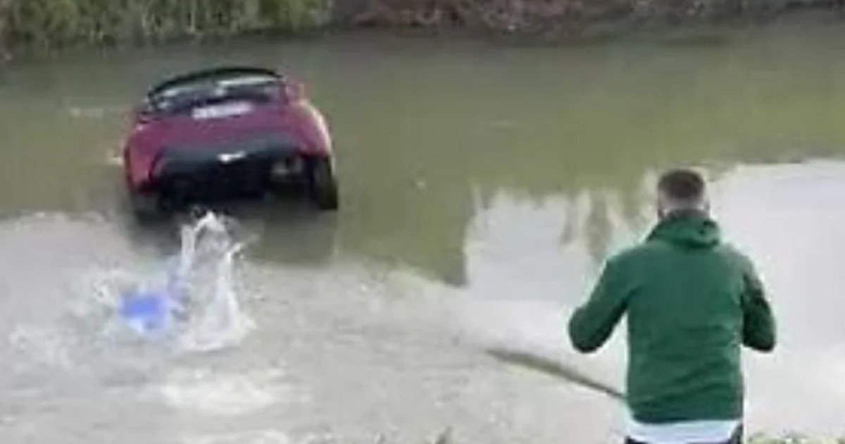 Un bărbat se pregătește să intre într-un canal în care o mașină stă să se scufunde, în Italia, noiembrie 2025
