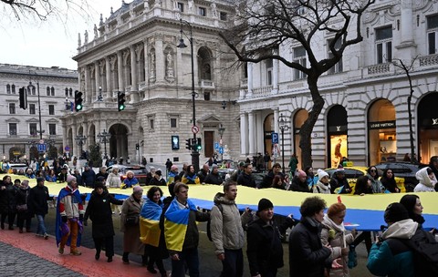 Oamenii poartă un steag ucrainean uriaș în fața Ambasadei Rusiei în cadrul unui marș de solidaritate în sprijinul Ucrainei, organizat la Budapesta, duminică, 22 februarie 2026
