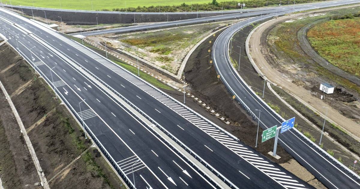 autostradă nou construită cu mai multe benzi pe fiecare sens de circulație și marcaje rutiere. nod rutier cu bretele de acces și ieșire. indicatoare rutiere pentru direcțiile de mers și parapete de siguranță