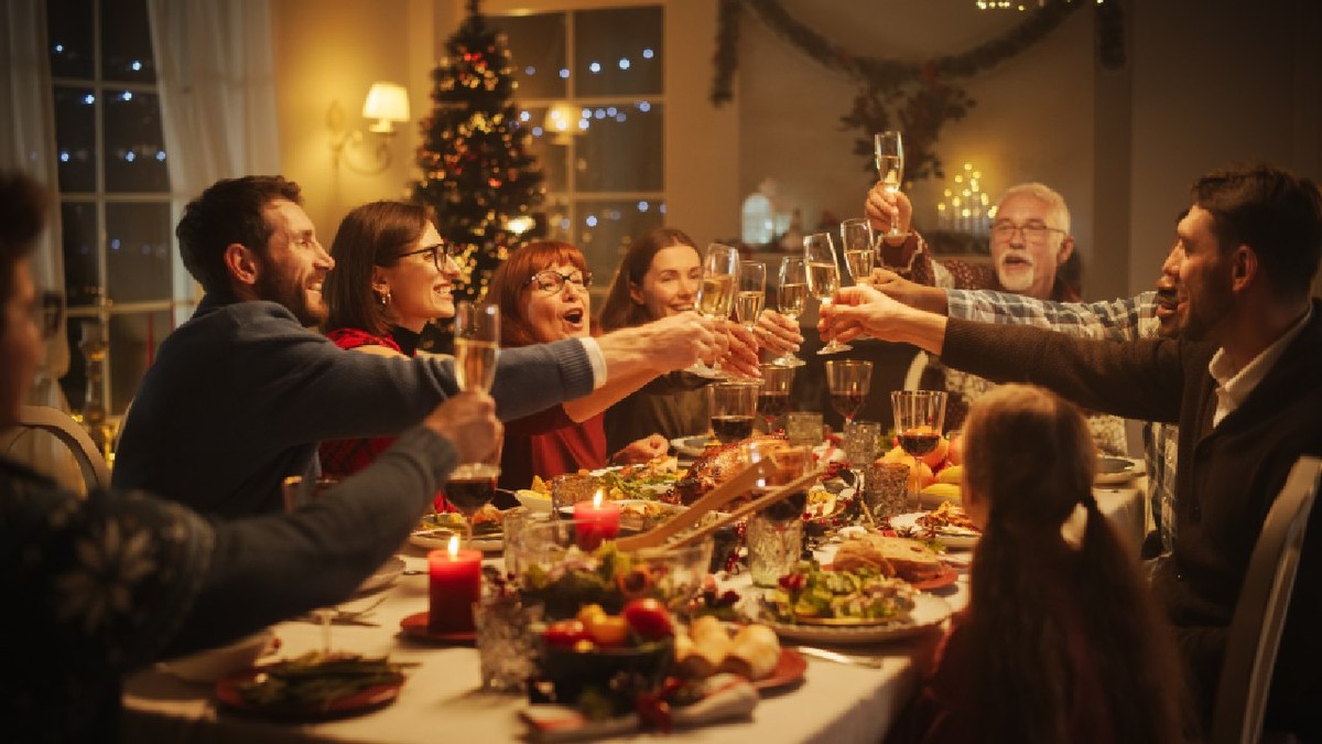 Portretul unui tânăr care propune un toast la masa de Crăciun. Familia și prietenii împărtășesc masa, ridică paharele cu șampanie, toastează și sărbătoresc sărbătorile de iarnă.