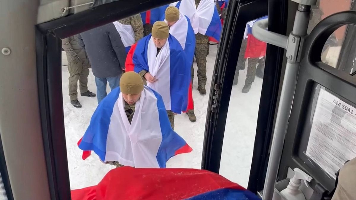 Mai multi militarii ruși care au fost eliberați din captivitate se urcă într-un autobuz având pe spate steagul Rusiei, 5 februarie 2026