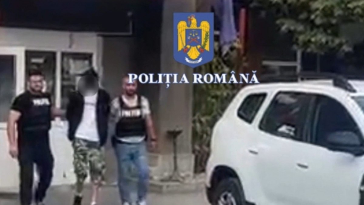 un bărbat este escortat de doi polițisti, în imagine se vede si o Dacia Duster albă