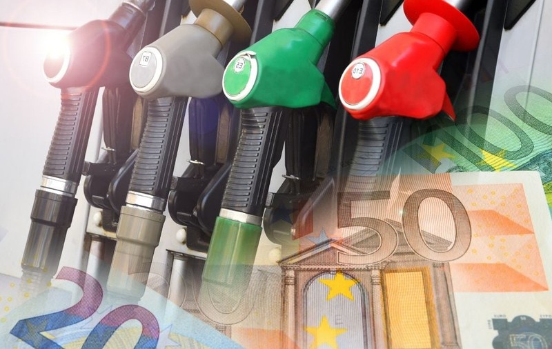 Imagine creativă cu pompe de benzină și motorină de culoare roșu, verde și negru, iar în partea de jos a fotografiei, bancnote de 20 și 50 de euro în blur