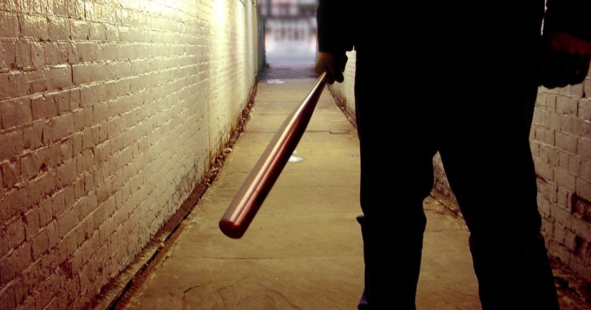 Silueta unui barbat bătăuș neidentificat cu o bâtă de baseball in mana dreapta într-un tunel