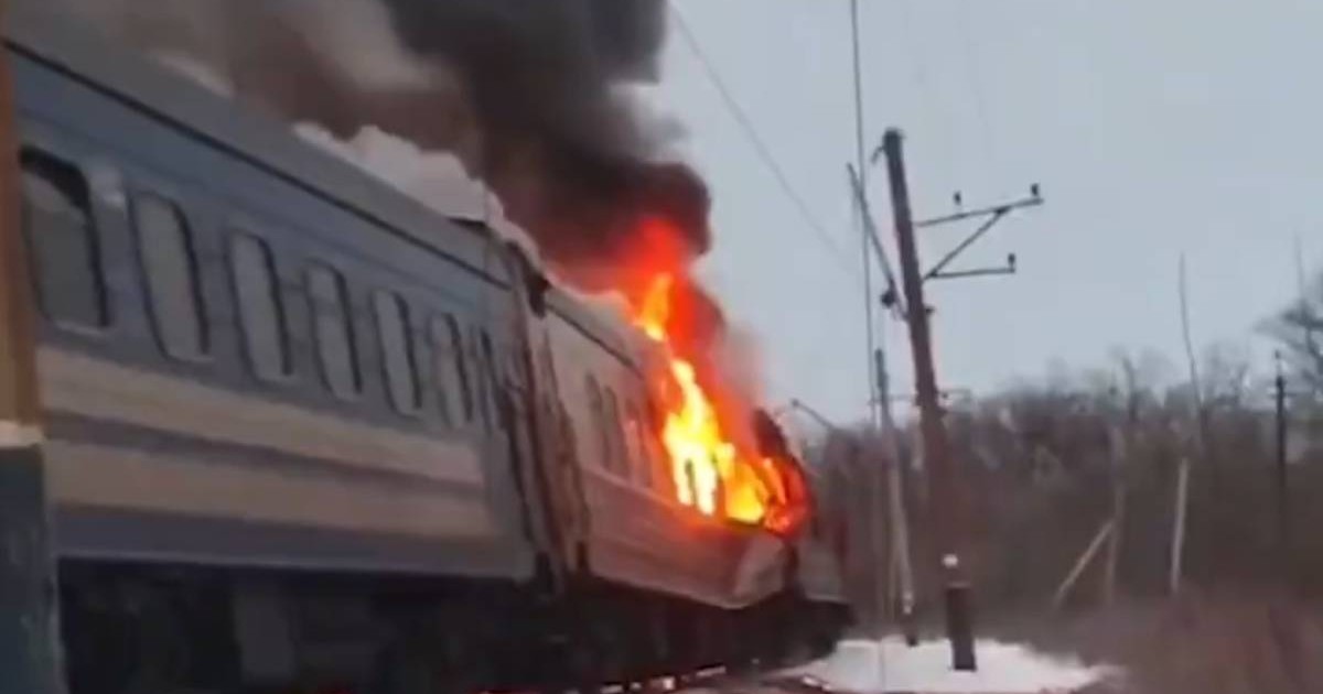 Imagine cu un tren in flăcări, se vede fum negru, iarna, e zapada pe jos, dupa un atac cu drone rusesti in Harkov, Ucraina