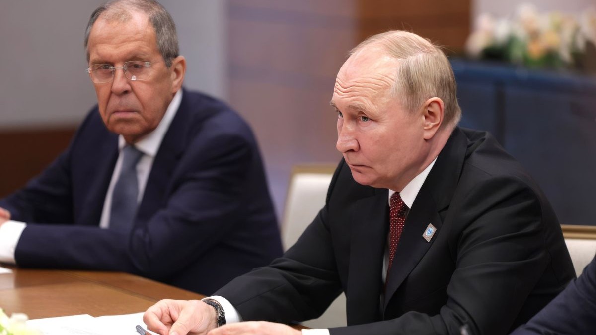 Președintele Rusiei, Vladimir Putin, în dreapta, alături de ministrul rus de Externe, Serghei Lavrov, în stânga, stau la o masă mare și discută
