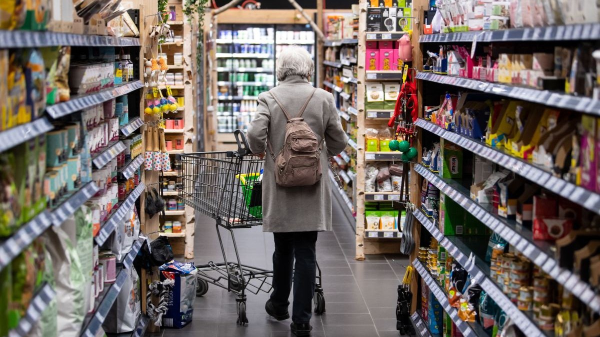 O femeie se plimbă printr-un supermarket din Germania cu coșul de cumpărături, martie 2022