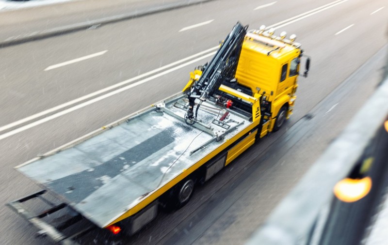 Un camion cu platformă pentru tractare, în timp ce circulă pe șosea