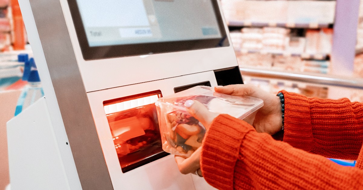 O femeie scanează un produs la o casă de marcat de tip self-service într-un supermarket