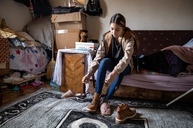 Maria se încalță cu ghetele noi, primite cadou de la unul dintre muncitorii care au lucrat la casă
