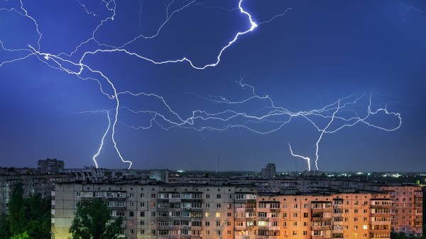 Furtună cu fulgere peste un oraș, cu blocuri în parte de jos a pozei, pe timp de noapte
