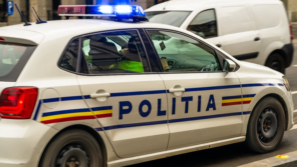 O mașina de Poliție cu doi polițiști în față și sirenele pornite, în timp ce se deplasează la o intervenție