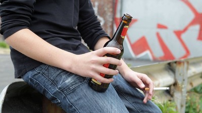 adolescent cu o bere in mana si o țigară în cealaltă