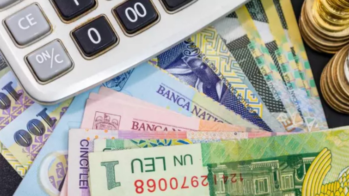 Un calculator așezat peste o sumă de bancnote de lei românești și teancuri de monede aurii și argintii