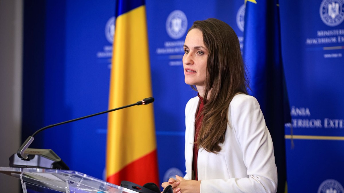 Oana Țoiu, ministrul Afacerilor Externe, în timpul unei conferințe de presă la MAE. Poartă o rochie vișinie și un sacou alb