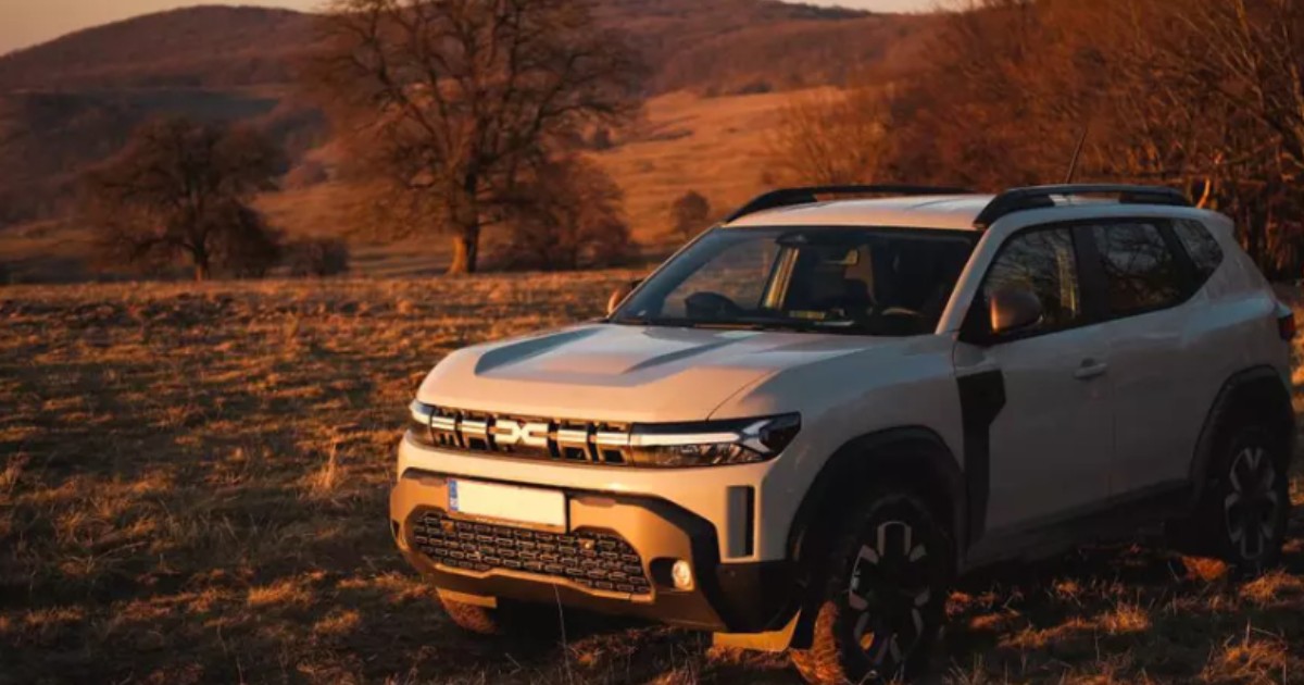 O mașină albă, marca Dacia Duster în lumina liniștitoare a unui apus