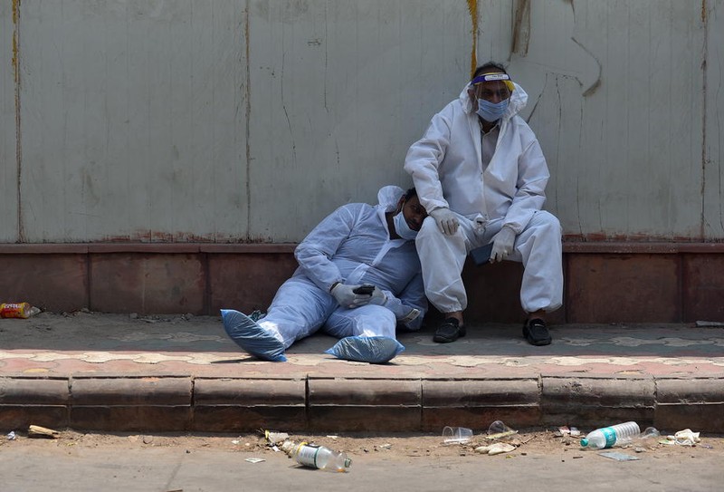 Două cadre medicale se odihnesc în fața unui spital din New Delhi | Foto: EPA