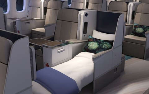 O cabină de avion din clasa business este echipată cu scaune individuale spațioase ce includ perne decorative, mese rabatabile și opțiunea de a se transforma într-un pat orizontal complet întins