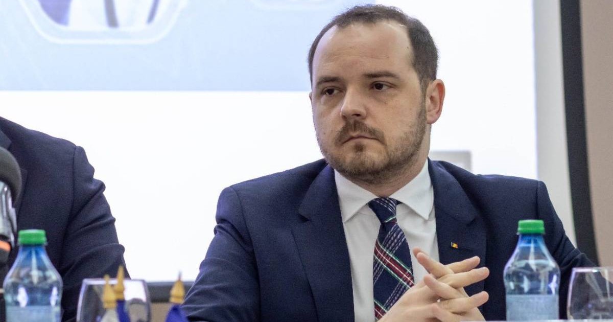 Alexandru Rogobete, ministrul Sănătății, îmbrăcat la costum, în timpul ședințe de la Iași, are mâinile încrucișate pe masă și privește atent în partea stângă