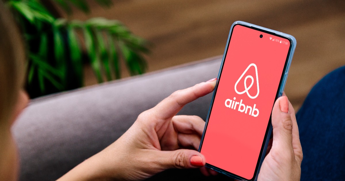 O femeie care intră pe Airbnb pe telefon
