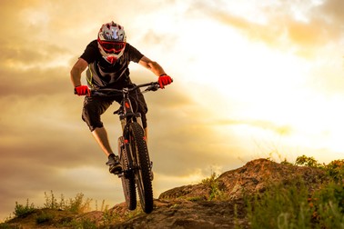 Professional Cyclist Riding the Bike Down Rocky Hill at Sunset. Extreme Sport Concept. Space for Text.