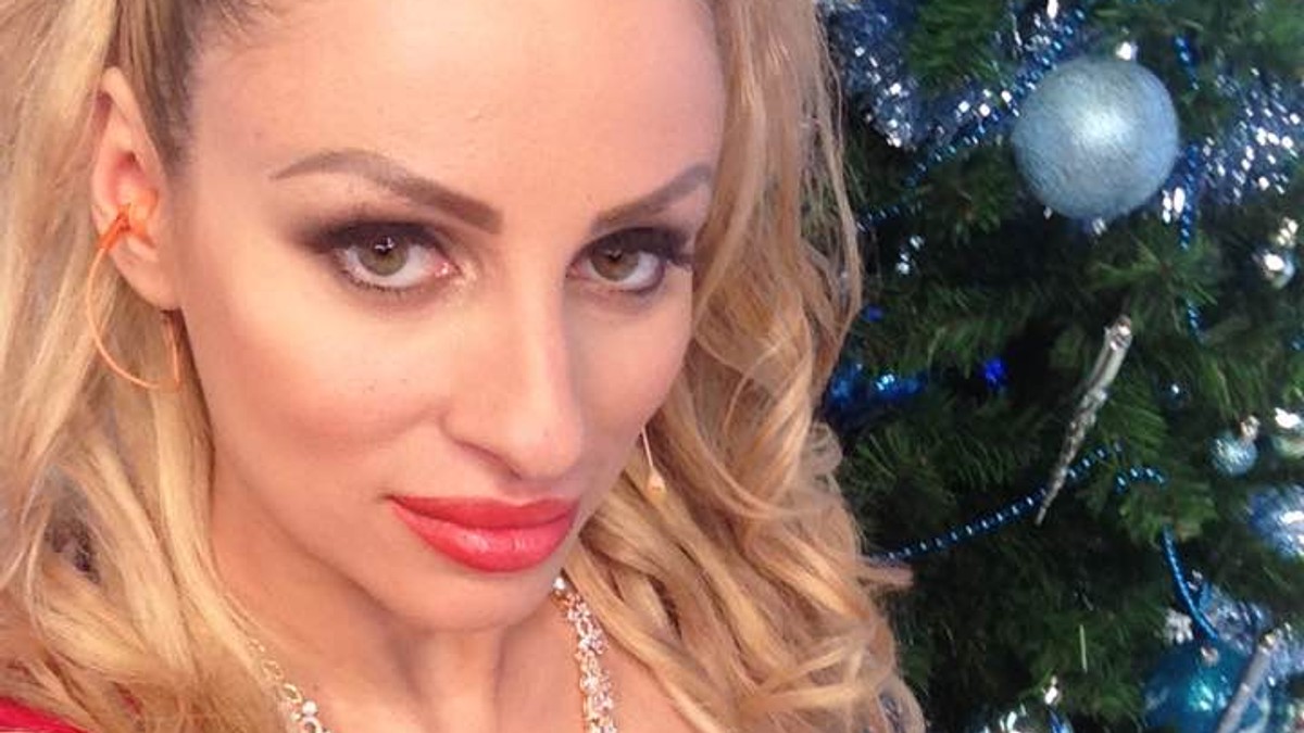 Sanziana Buruiană, îmbrăcată într-o rochie roșie cu decolteu adânc, pozează lângă bradul de Crăciun
