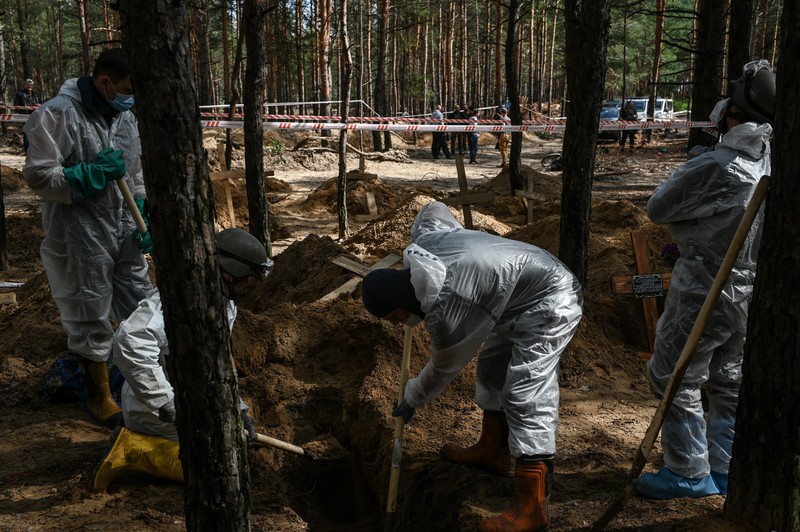 Experții criminaliști ucraineni sapă și exhumează rămășițele dintr-un mormânt nemarcat într-o groapă comună din Izium. Foto: Profimedia