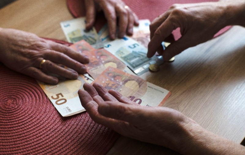 Doi bătrâni care numără bancnote euro