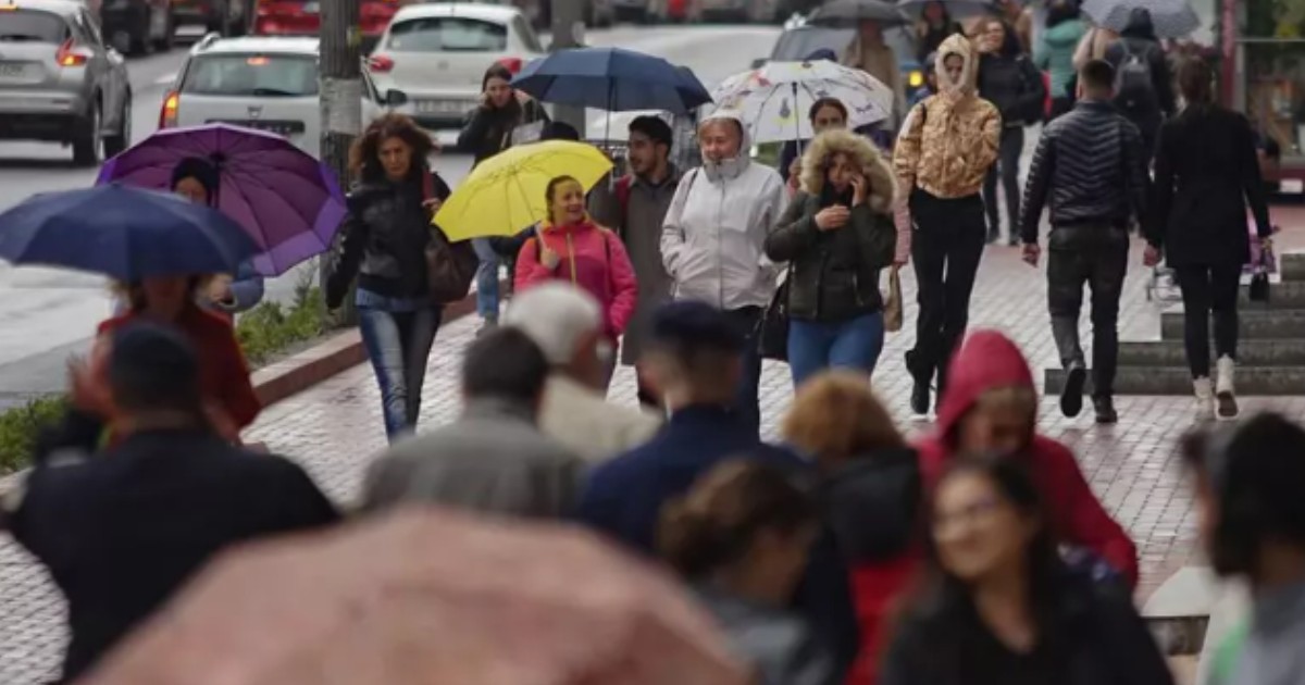 Oameni care merg pe stradă cu umbrele într-o zi ploioasă.