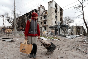 O femeie prin Mariupol, mergând printre ruinele orașul. Fotografie din 18 aprilie. Foto: Profimedia.