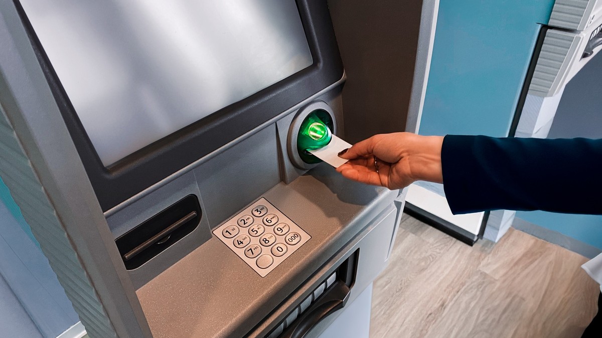 Femeie care introduce un card în ATM