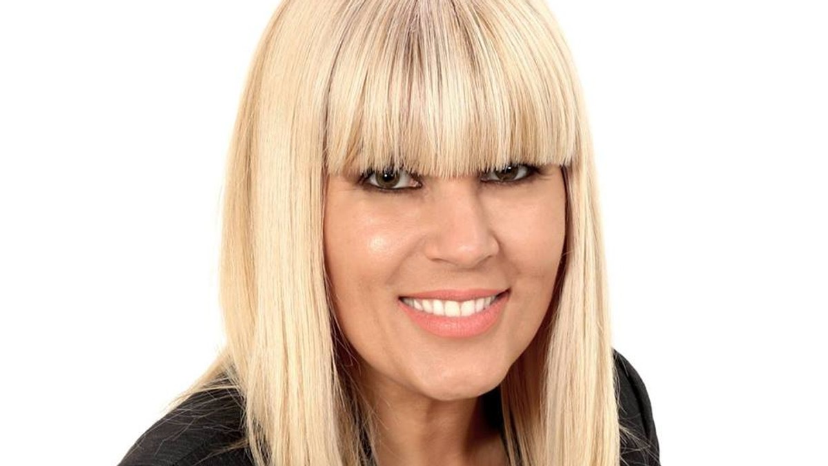 Elena Udrea a transmis un mesaj din Costa Rica despre mitingul PSD. Elena Udrea, zambind, cu breton, un sacou negru și o bluza albă, cu decolteu generos