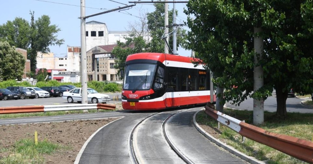 Un tramvai Imperio roșu care merge pe șine în Arad, în timpul primăverii, în timp ce transportă pasagerii