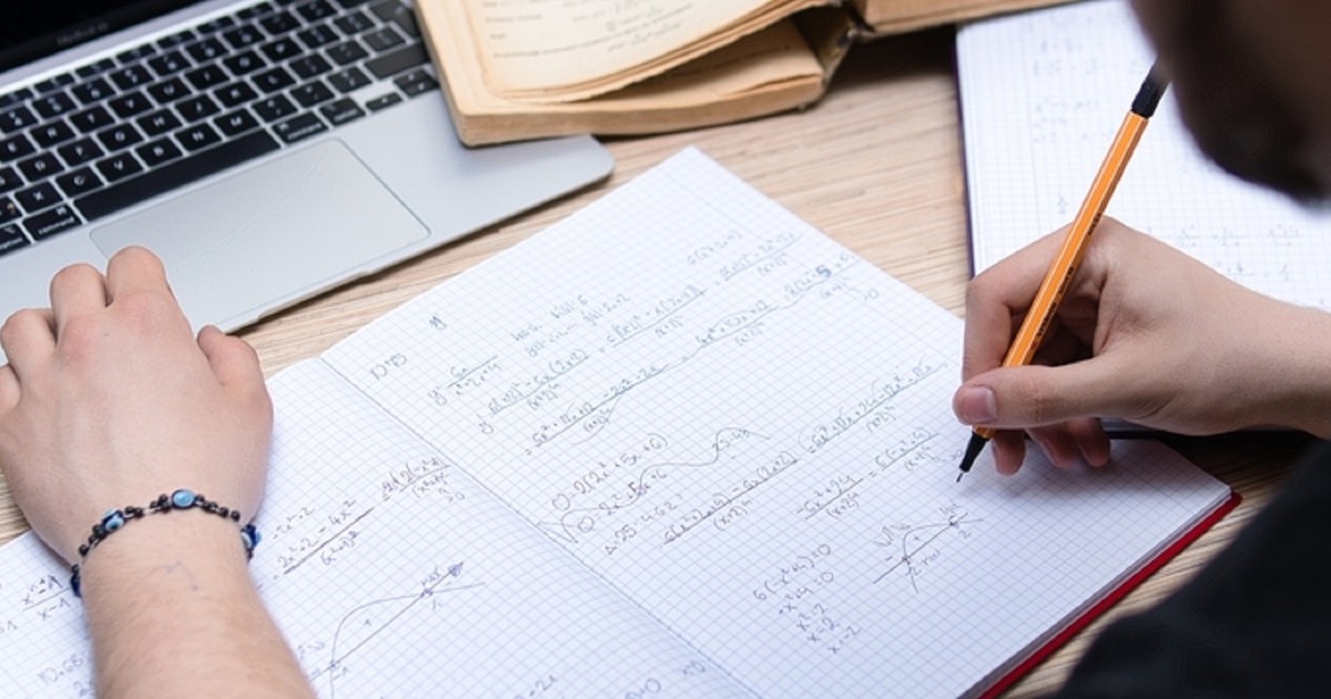Ce este o expresie numerică - Imagine cu un elev care rezolvă ecuaţii matematice pe un caiet studenţesc