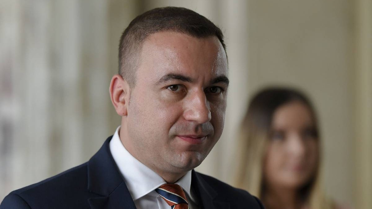 În imagine Bogdan Ivan, îmbrăcat la costum, privește spre aparatul foto